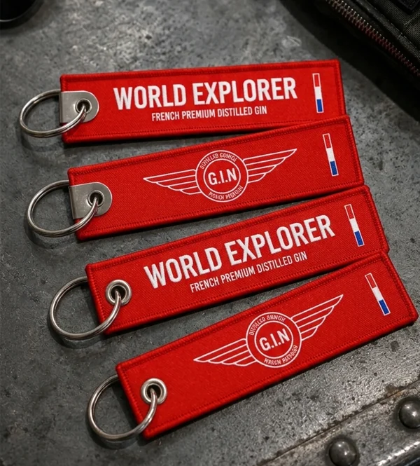 Flammes porte-clés World Explorer rouges, faces World Explorer et G.I.N, posées sur une surface métallique